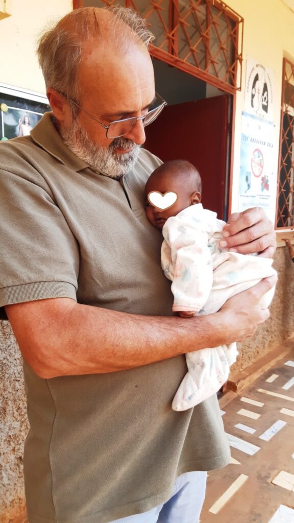 Don Vittorio Giglio con un neonato